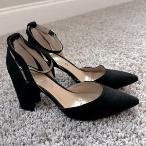 Black pumps with ankle strap and pointed toe